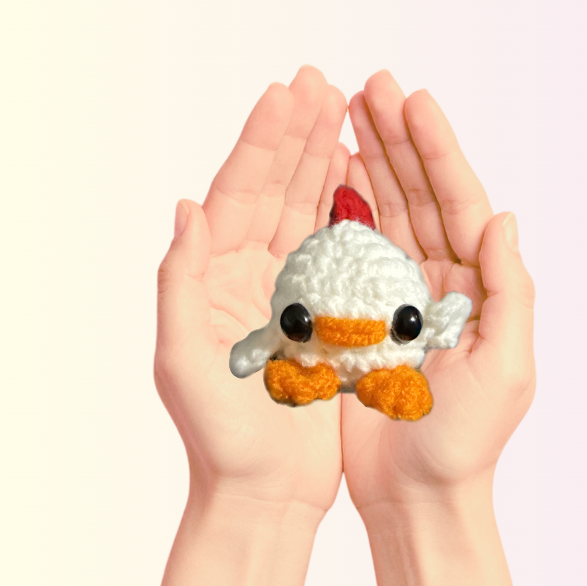 Chunkle Puff Cat Toy Scale Image. Tiny white woven chick cat toy with black eyes, orange beak and feet, and red comb resting in two cupped hands, showing its petite palm-sized scale and soft textured yarn surface.