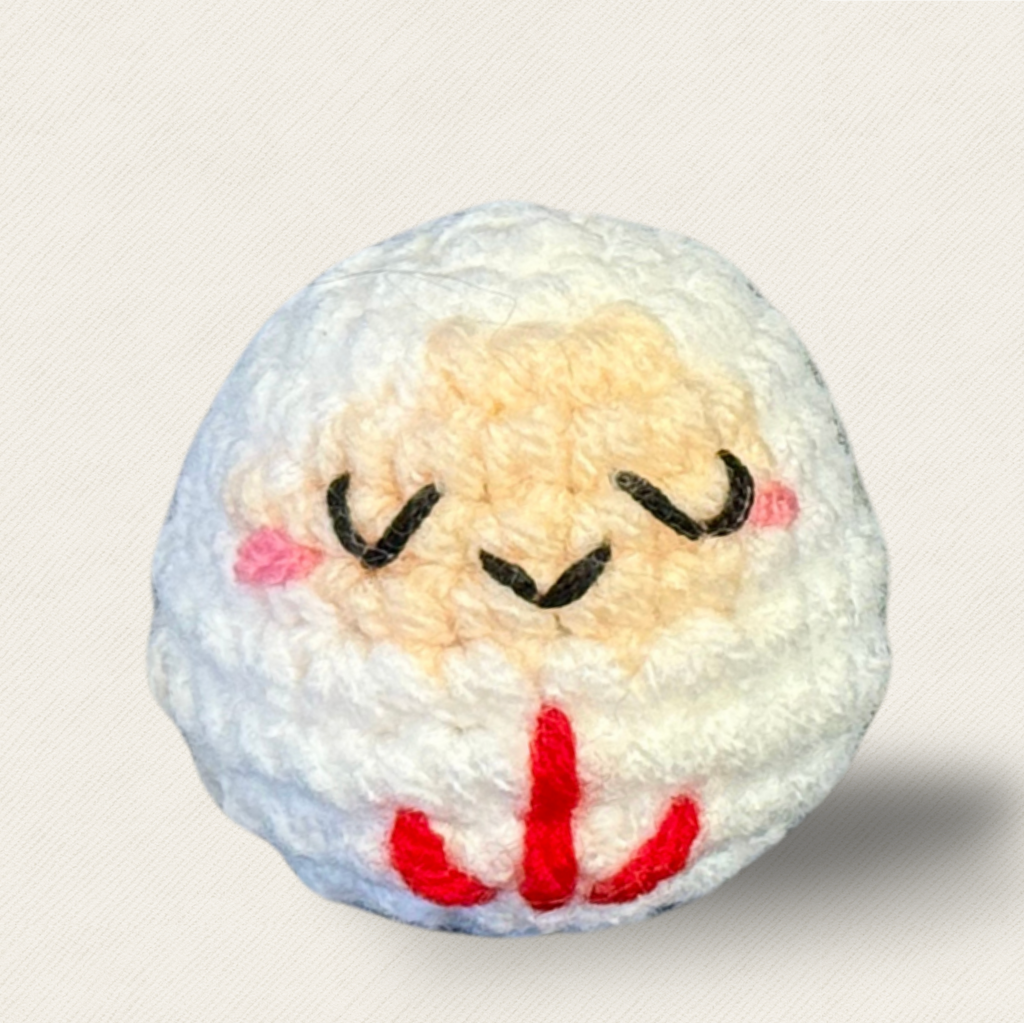 Japanese Cat Toy Daruma Doll In White. White daruma doll cat toy named Mochi on a white background, showing its rounded shape, closed embroidered eyes, plush texture, and red stitched details.