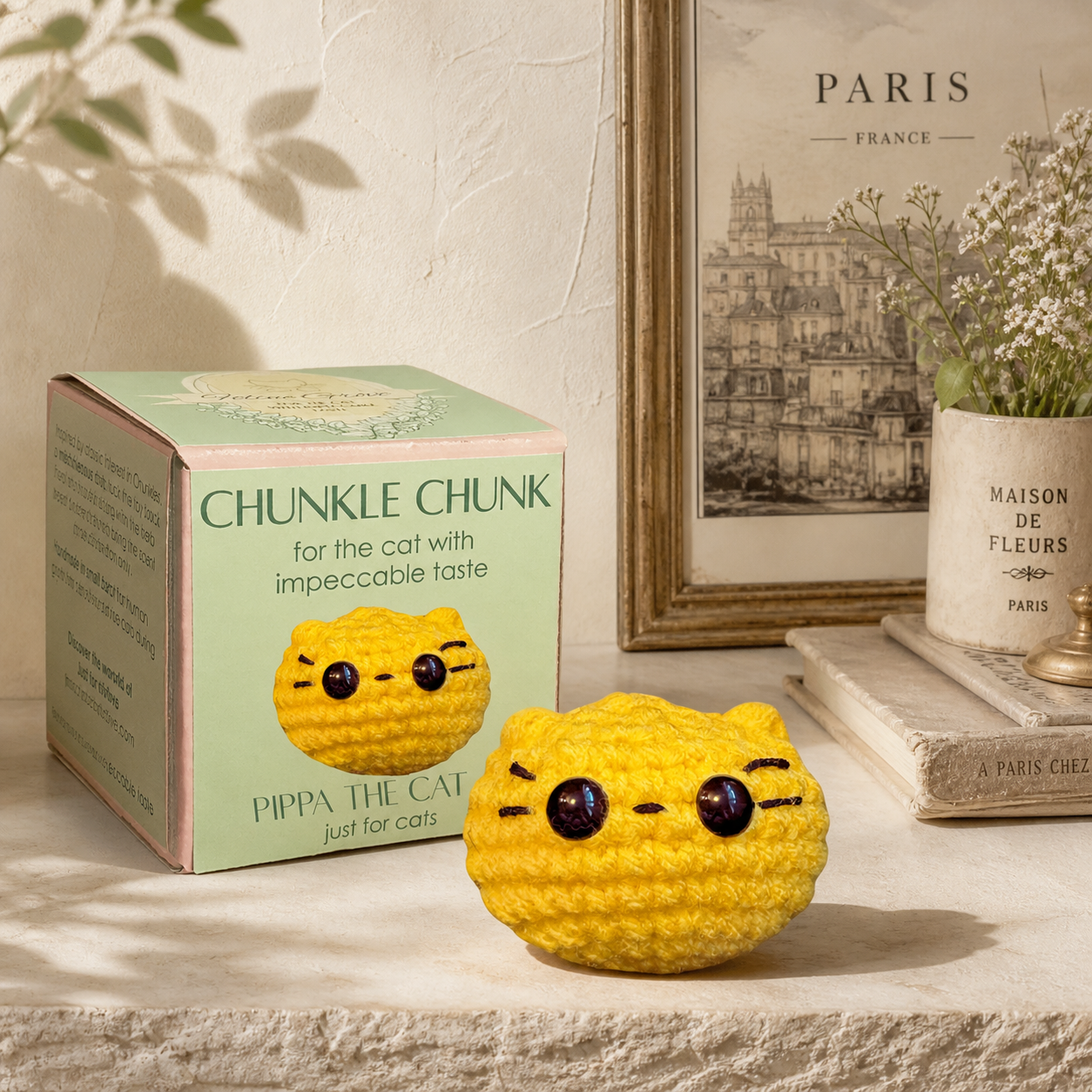Round yellow weighted Chunkle Chunk catnip alternative cat toy with packaging in a stony background.