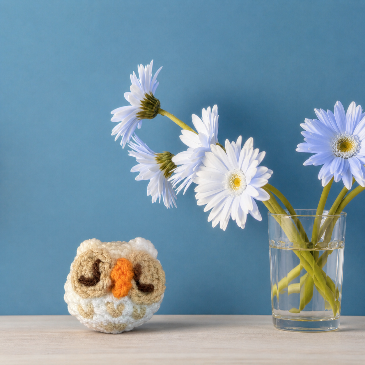 Snowy owl shaped woven cat toy styled on shelf with blue daisies, botanical catnip alternative cat toy by Chunkle and Puff Feline Grove.