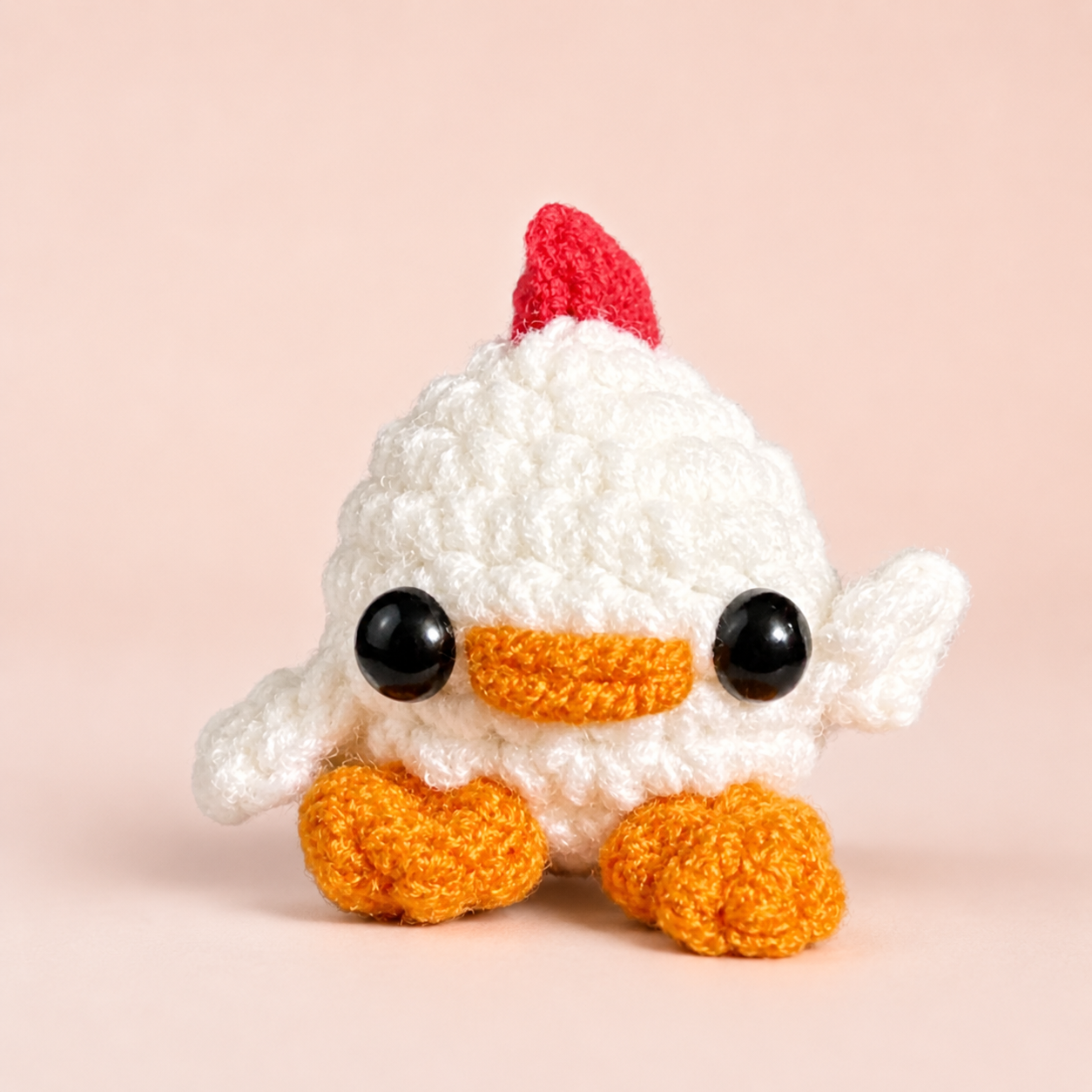 Cat Toy Chick Weighted. Close front view of a tiny white woven chick cat toy with rounded body, plush yarn texture, glossy black eyes, orange beak and feet, and a red comb against a light fabric background.