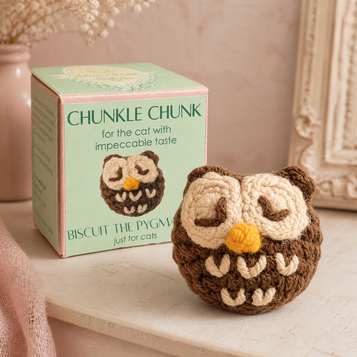 Biscuit the pygmy owl weighted cat toy shown with green Chunkle Chunk box on pink shelf