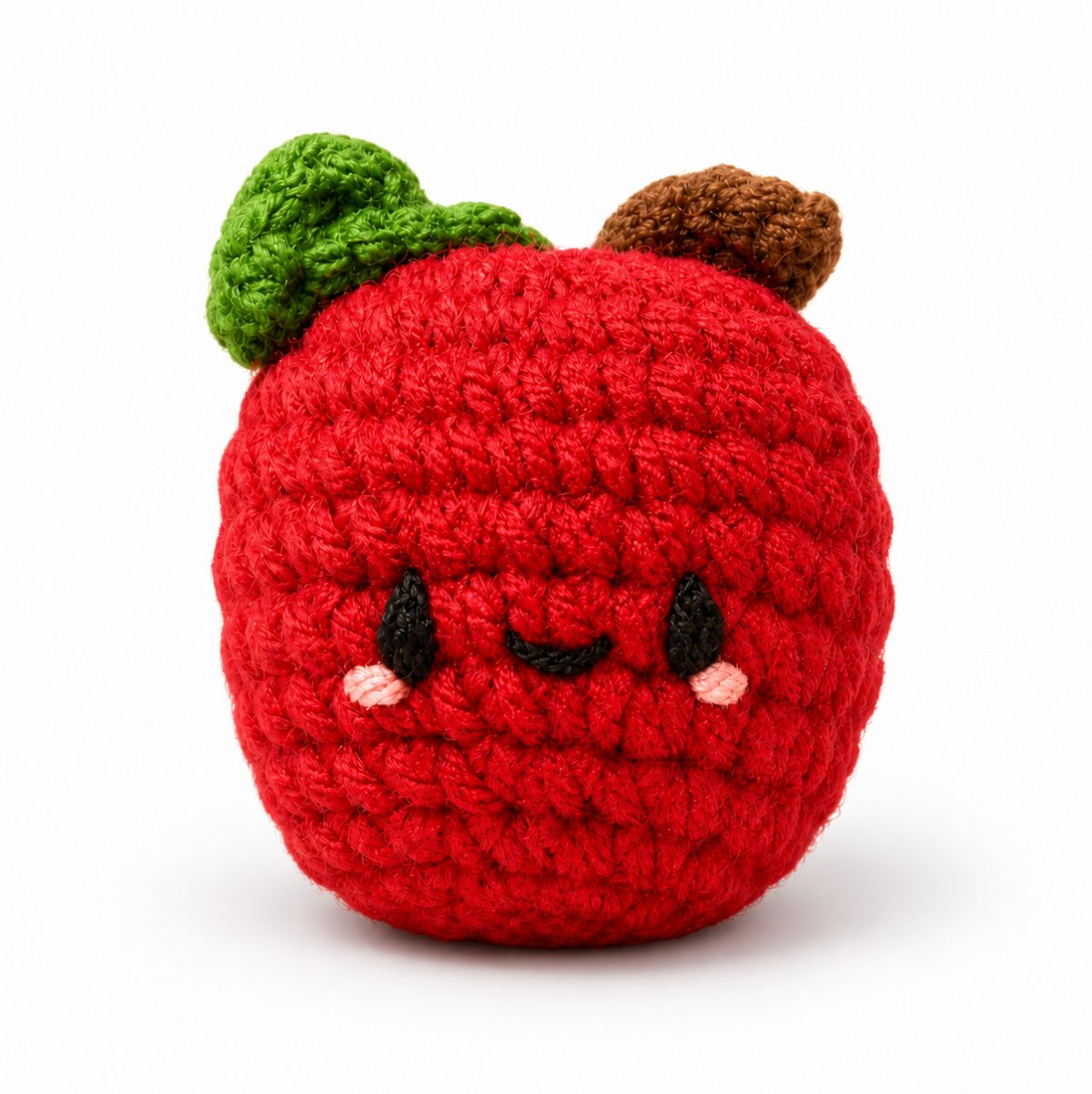 crocheted cat toy red apple with black face details, pink cheek details, a brown stem and a green leaf