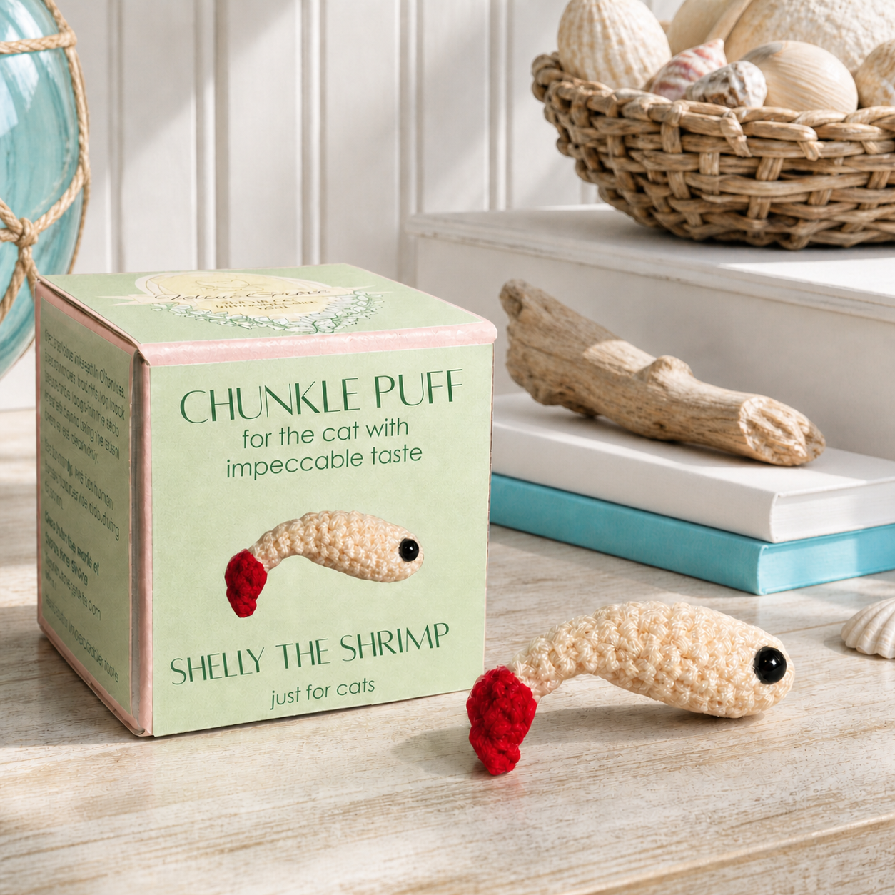 Woven shrimp cat toy displayed beside green Chunkle Chunk box labeled Shelly the Shrimp, ivory textured body with red tail, compact lightweight form, designer cat toy infused with Miracle Nip