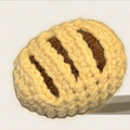 Chocolate croissant shaped woven cat toy close-up showing buttery yellow and chocolate brown detail, Miracle Nip botanical catnip alternative by Chunkle and Puff