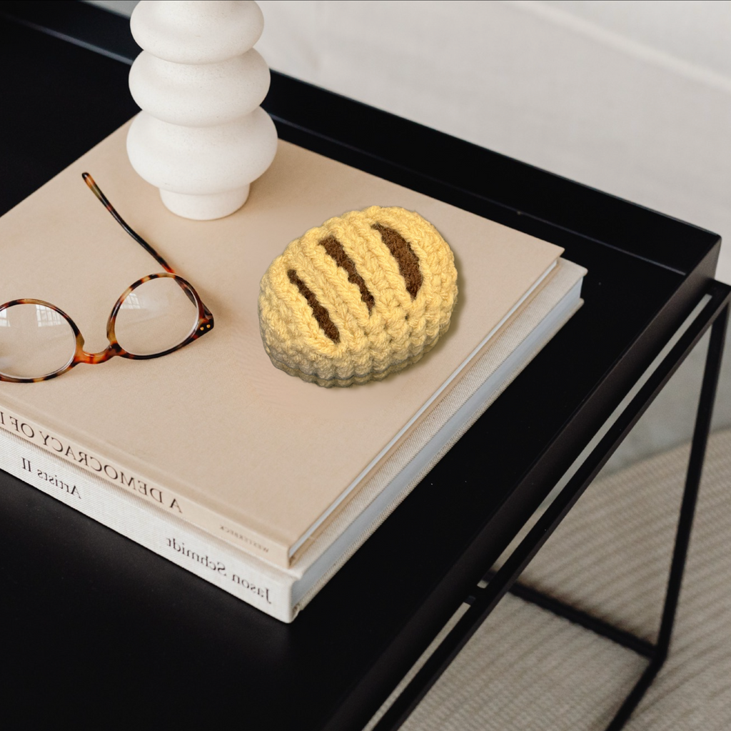 Chocolate croissant shaped Chunkle Puff cat toy styled on coffee table books, botanical independent play cat toy for indoor cats by Feline Grove