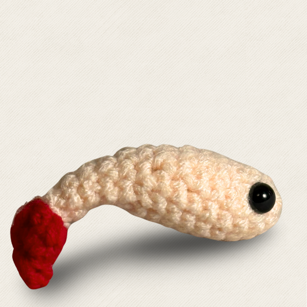 Woven shrimp cat toy in soft ivory yarn with curved body and red tail, textured surface and glossy black eyes, lightweight boutique Chunkle & Puff toy infused with Miracle Nip on neutral backdrop