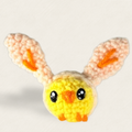 Wally the Chick artisan cat toy in yellow and peach yarn with upright ears and embroidered face, centered on a neutral fabric background; small, plush, hand-woven design clearly visible.
