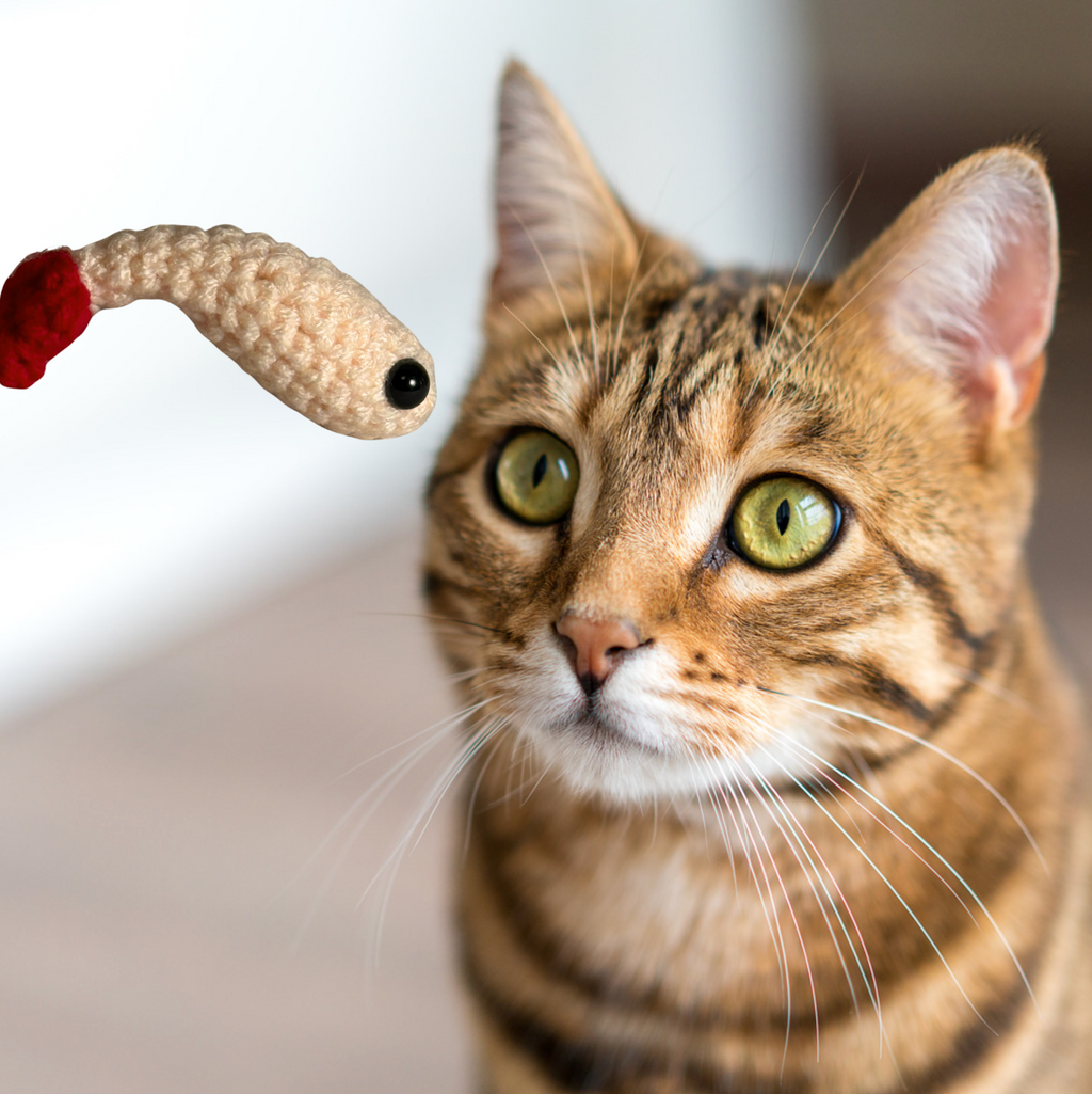 Bengal cat watching small woven shrimp cat toy mid-air, ivory yarn body with red tail, lightweight independent play toy sized for batting and chasing, Chunkle & Puff toy infused with Miracle Nip
