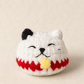 White woven lucky cat toy by Chunkle & Puff infused with Miracle Nip, soft plush texture with red trim and yellow detail, shown close-up on neutral fabric background