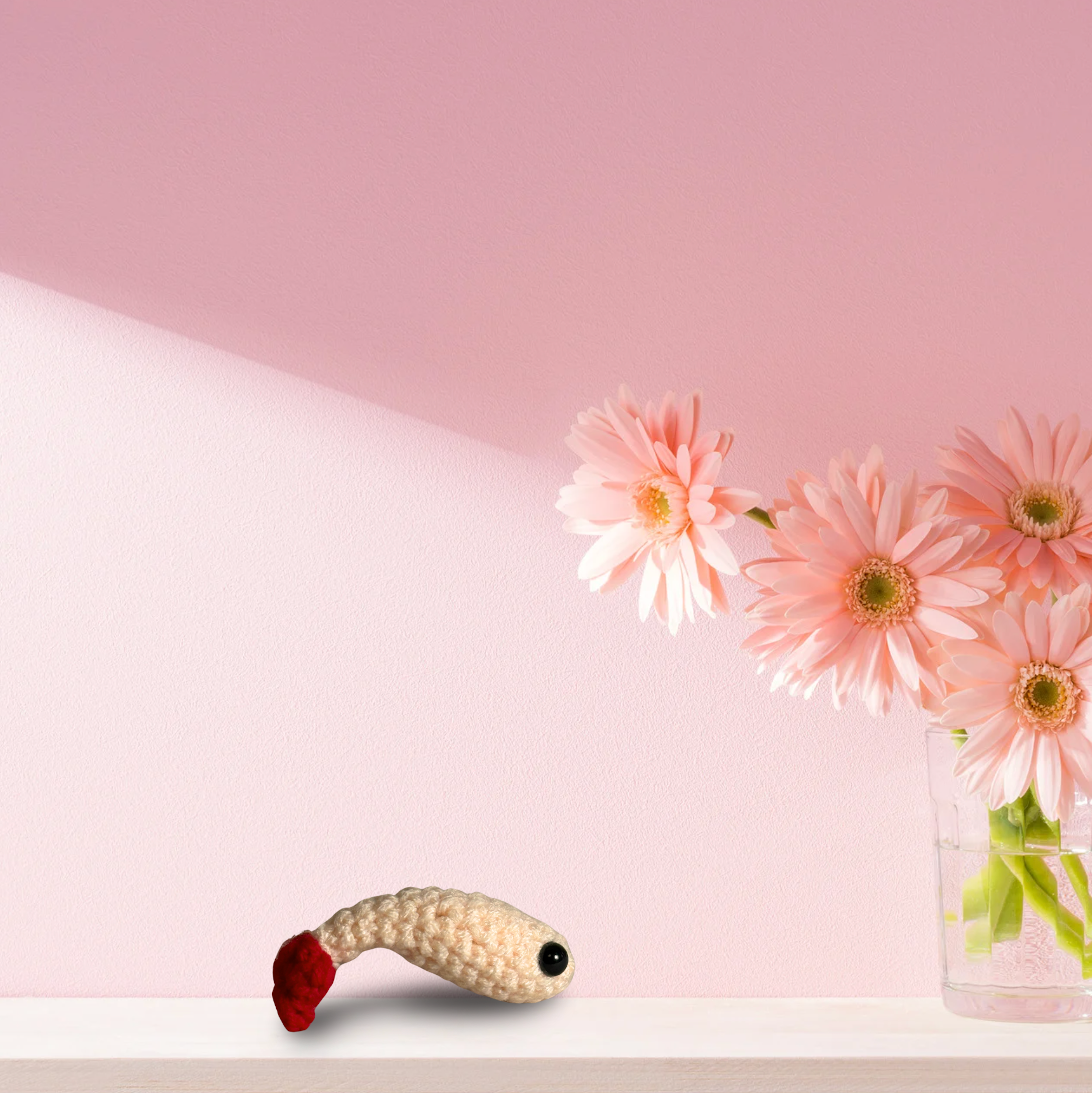 Woven shrimp cat toy resting on shelf beside soft pink flowers, ivory textured body with red tail, small decorative scale that blends into home decor, Chunkle & Puff toy infused with Miracle Nip